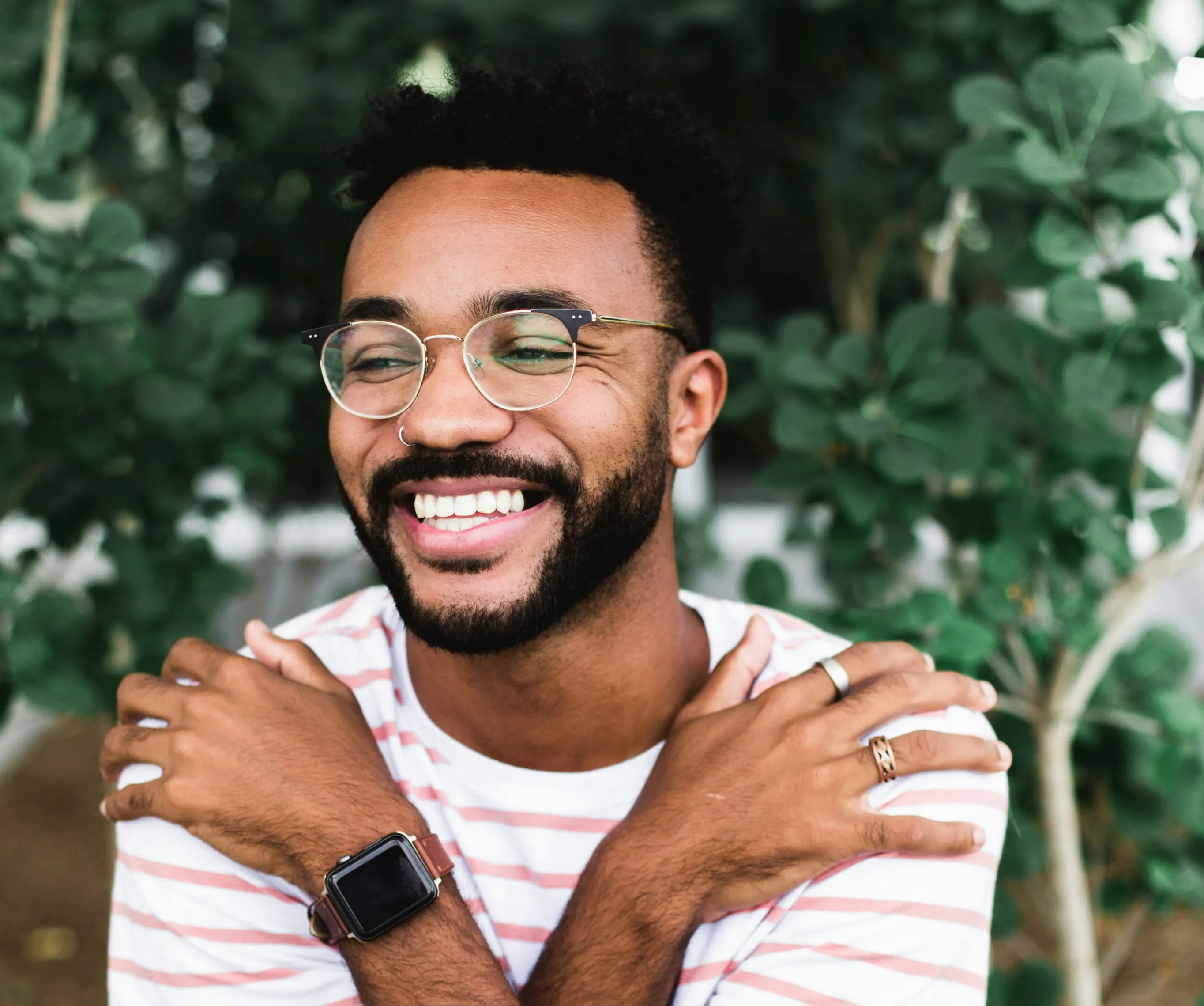A man smiling, arms crossed in a self-hug